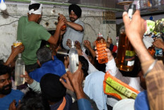 Devotees hold bottles of liquor as they offer at a shrine of a locally idolised divinity on the outskirts of Amritsar.