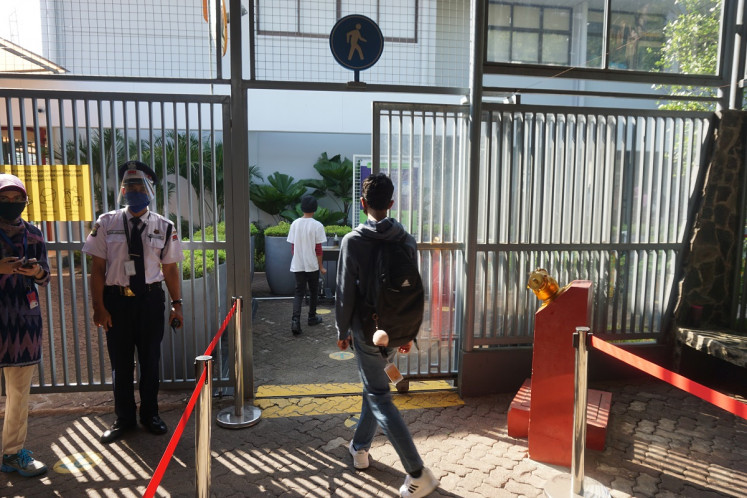 Students enter the school grounds while keeping safe distance after having their body temperatures checked in Lycée
Français de Jakarta, in Cipete, South Jakarta, on Friday, May 28, 2021. The school opened its doors on Friday to welcome elementary school principals keen to learn how to implement in-class learning while still adhering to strict health protocols.