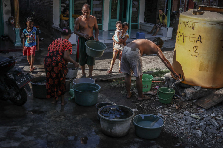 Water for life: The people of Gempol Sari village line up to fill containers with clean water on May 29, 2021 in Sidoarjo, East Java. A local nonprofit run by four youths, Komunitas Kecil Bergerak Indonesia (KKBI), provided five tanks that it fills every week with clean water, but one member says he has received death threats for helping the village.