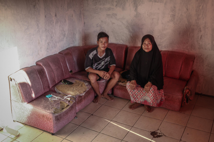 Strict minimum: Warsita sits with her grandson on May 29, 2021 at their home in the village of Gempol Sari, which was flooded with mud at the start of the 2006 mudslide disaster in Sidoarjo, eastern Java. 