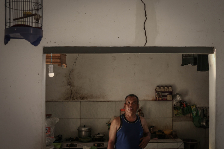 'Chicken Little': Sukardi stands below a cracked wall in his house in Gempol Sari village in Sidoarjo, East Java, on May 29, 2021, the 15th anniversary of the Sidoarjo mudflow disaster. He is under constant strain from worrying that his house will collapse at any moment, as the land it stands on is sinking as a result of the disaster. 