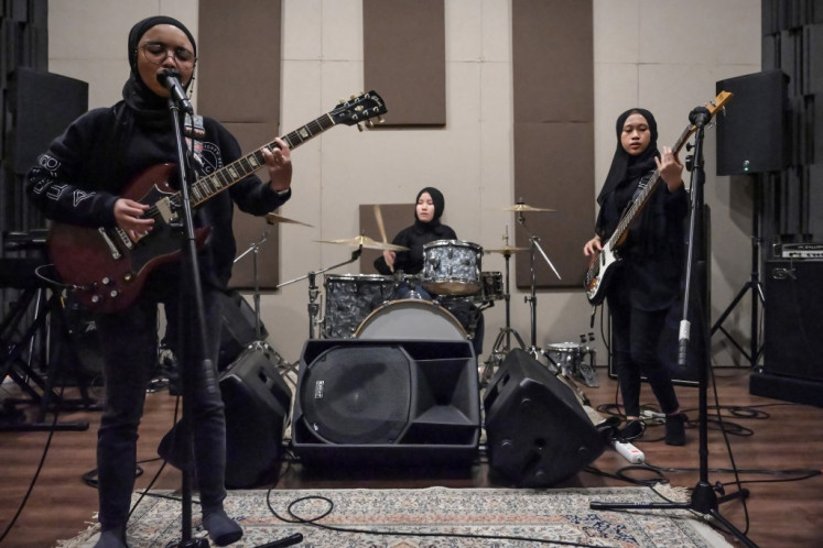 In this picture taken on April 8, 2021, members of the Indonesian heavy metal band Voice of Baceprot (VOB), guitarist and vocalist Firda Marsya Kurnia (L), drummer Euis Siti Aisah (C) and bassist Widi Rahmawati (R) perform during a practice session in Jakarta.