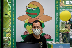 The photo taken on May 29, 2021 shows a man sitting in front of a poster of Pepe the Frog at a shopping mall in Beijing. Ground down by the sapping realities of modern city life, China's youth are 