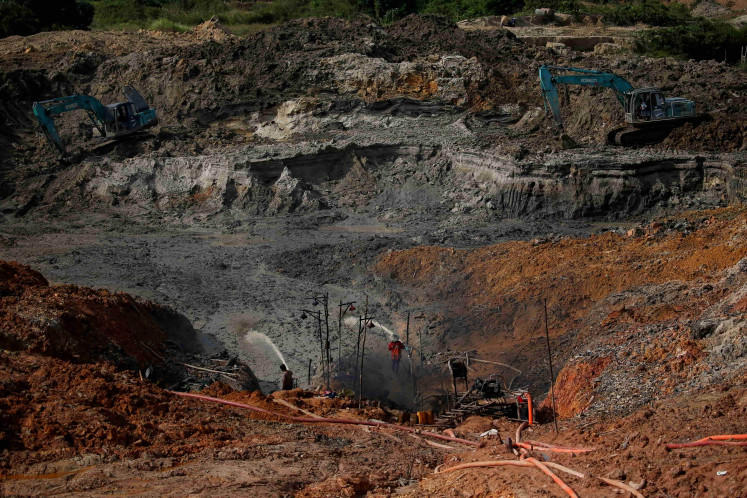 Unlicensed miners work in a tin mining area in Toboali, on the southern shores of the island of Bangka, Indonesia, April 29, 2021. Miners who continue working on land have to deploy expensive heavy machinery to dig deeper for tin ore as reserves dwindle.