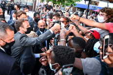 French President Emmanuel Macron (left) interacts with members of a crowd while visiting Valence on June 8, 2021 during a visit in the French southeastern department of Drôme, the second stage of a nationwide tour ahead of next year's presidential election.
