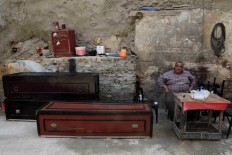 Mohamed Mahmoud, 65 years old a traditional undertaker looks on near lacquered wooden coffins and accessories at a working area in the Shobra district of Cairo, Egypt. 