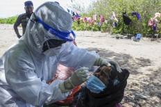 A health worker from the East Aceh Health Agency stores a COVID-19 antigen swab sample, taken from a Rohingya refugee at a shelter on Idaman Island, Simpang Ulim district, Aceh, on June 9, 2021. According to the UN Refugee Agency (UNHCR), Indonesia currently hosts around 13,200 refugees, including 3,000 children, who remain outside the government's COVID-19 health and safety schemes.