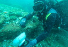 This undated handout photo from the ISEAS - Yusof Ishak Institute released on June 16, 2021 shows a diver holding a bowl with Chinese characters that was discovered from a shipwreck in the waters off Pedra Branca, Singapore.
