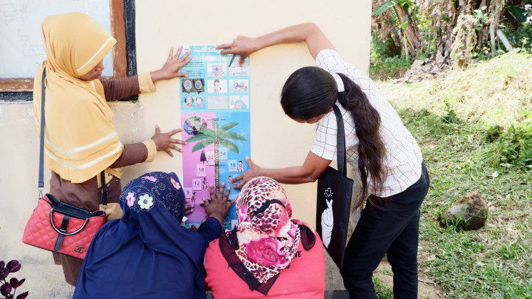 Community effort: Health workers install a Smart Chart for measuring children's physical growth at a resident's home in West Manggarai regency, East Nusa Tenggara.