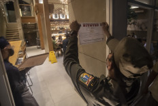 A Jakarta Public Order Agency (Satpol PP) officer puts up a warning sign on the window of a restaurant in Jakarta on June 13. The agency closed down the restaurant after it was found to be violating the COVID-19 health protocols. 
