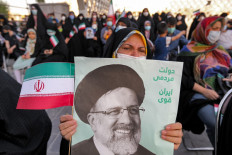 A woman holds a poster of Iran's newly-elected president Ebrahim Raisi, with text in Persian reading 