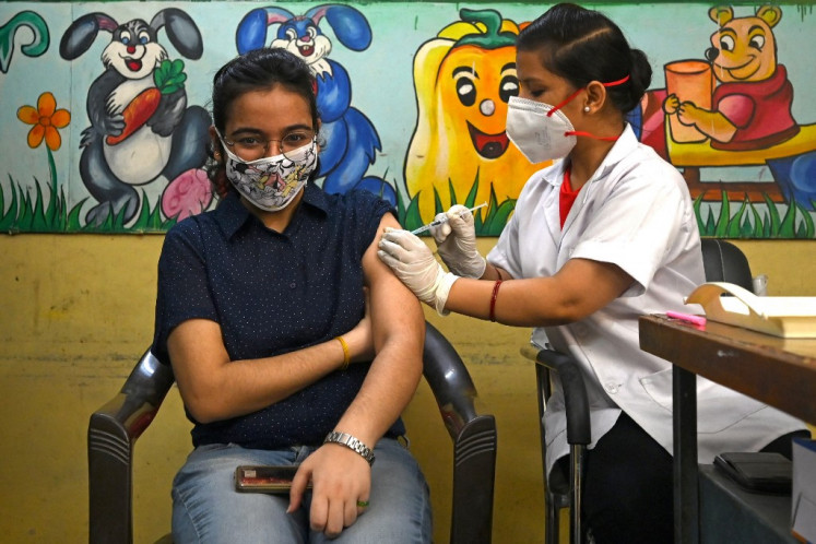 A health worker inoculates a woman with a jab of Covishield's Covid-19 Coronavirus vaccine at a vaccination Centre in New Delhi on June 21, 2021 after India opened up free vaccinations to all adults.