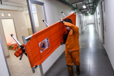 A Jakarta public facilities and maintenance worker carries a portable cot on June 21, 2021 to help set up the government-run isolation center at the Nagrak low-cost apartment (Rusunawa) in Cilincing, North Jakarta.