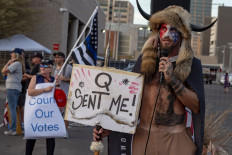 Jake Angeli, known as the "QAnon Shaman," holds a sign reading "Q Sent Me" as supporters of US President Donald Trump gather to protest outside the Maricopa County Election Department as counting continues after the US presidential election in Phoenix, Arizona, on November 5, 2020. President Donald Trump erupted on November 5 in a tirade of unsubstantiated claims that he has been cheated out of winning the US election as vote counting across battleground states showed Democrat Joe Biden steadily closing in on victory.