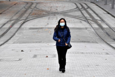 A woman wearing a face mask walks towards a light rail station in Sydney on June 23, 2021, as residents were largely banned from leaving the city to stop a growing outbreak of the highly contagious Delta Covid-19 variant spreading to other regions. 