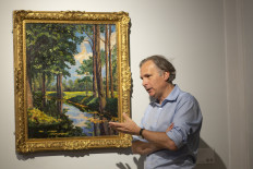 In this file photo taken on June 18, 2021 Jean Paul Engelen, Deputy Chairman and worldwide co-head of 20th century and contemporary art at Phillips Auction House speaks next to "The Moat, Breccles" painting made by Winston Churchill and owned by the Onassis family, in New York. A painting by wartime British Prime Minister Winston Churchill that was gifted to Greek shipping magnate Aristotle Onassis sold for $1.85 million at a Phillips auction in New York on June 23, 2021. "The Moat, Breccles," a signed 1921 oil landscape, went for within its pre-sale estimate price of between $1.5 million and $2 million.