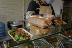Food vendor worker serving rice on Plépah's food container made with areca palm’s midrib, a green alternative to Styrofoam. 