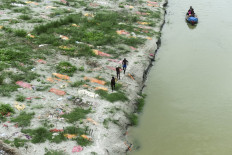 Fishermen pull a boat as they walk amidst shallow graves of people buried on the banks of the Ganges River during the Covid-19 pandemic, near a cremation ground in Allahabad on June 25, 2021.
