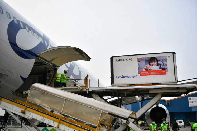 Significant items: Workers unload containers of Sinovac bulk vaccines from the airplane’s fuselage on Sunday. 