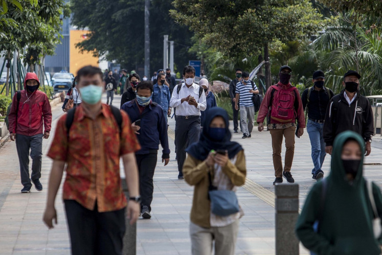 Office workers walk near the Dukuh Atas railway station in Central Jakarta in June 2021. 