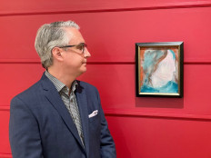 A handout photo released on June 15, 2021, courtesy of the auction house Cowley Abbott shows Canadian Art Specialist Rob Cowley looking at a painting by British pop icon David Bowie in Toronto, Canada. A painting by British pop icon David Bowie recently discovered at a Canadian store that resells donated goods had frantic bidders lining up for a chance to own it June 15, 2021.
