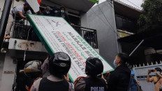 Outlawed: Police and military personnel remove the signboard of the Islam Defenders Front (FPI) in Petamburan, Central Jakarta on Dec. 30, 2020. The government banned the radical group after refusing to extend its permit as a mass organization. 