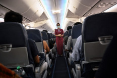 This photo taken on June 29, 2021 shows a Thai Lion Air hostess amongst passengers on a domestic flight from Bangkok to Phuket, before take-off at Don Muang Airport in Bangkok, days before the “Phuket Sandbox” tourism scheme that allows visits by people vaccinated against the Covid-19 coronavirus is set to launch.