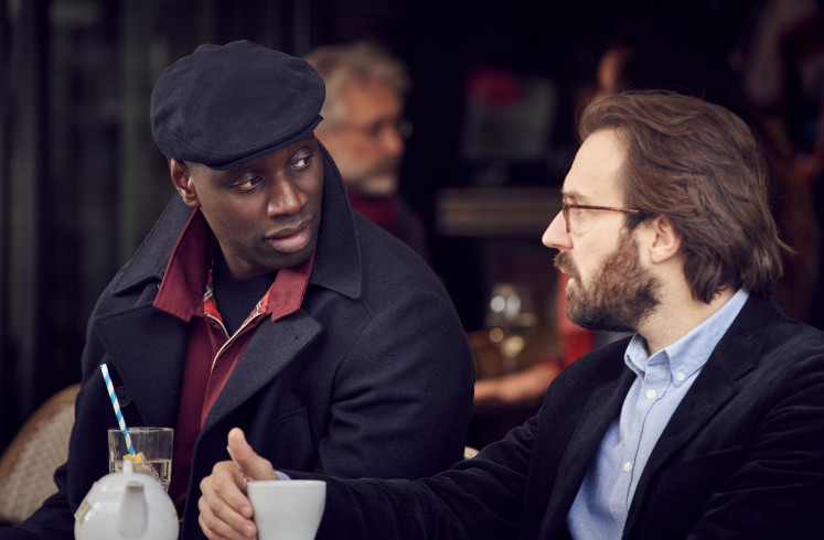 Slick duds: Omar Sy (left) portrays the titular character of Neflix's 'Lupin', Assane “Lupin” Diop. He also executive produces the not-so-faithful adaptation of the classic French novel by Maurice Leblanc, set in the gritty reality of modern-day Paris.