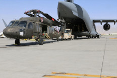 In this handout photo taken on June 16, 2021 and released on June 29, 2021 by the US Defense Visual Information Distribution Service (DVIDS) Aerial porters work with maintainers to load a UH-60L Blackhawk helicopter into a C-17 Globemaster III in support of the Resolute Support retrograde mission in Bagram. 