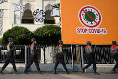 Police march past a billboard related to stopping the spread of the Covid-19 coronavirus as protesters gather for a demonstration against the military coup in Yangon on February 6, 2021. 