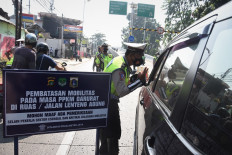 Police officers divert traffic leading to Jakarta at a checkpoint in Jl. Lenteng Agung in South Jakarta on July 3, as the government imposes emergency public activity restrictions (PPKM Darurat) in Java and Bali from July 3 to 20 to stem the alarming surge of COVID-19 cases.
