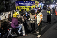 Security personnel check motorists' identity documents on Jl. Raya Bogor in East Jakarta on July 2. The government imposed emergency public activity restrictions (PPKM Darurat) across much of Java and Bali from July 3 to 20 to stem the alarming surge of COVID-19 cases. Officials recently extended the curbs for another week, with a view to relaxing the measures under a new system of community activity restrictions.