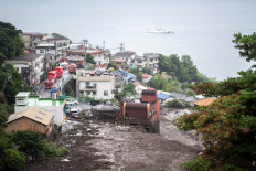 A Japan Coast Guard boat (top) on search and recovery patrol is seen beyond the path of a landslide following days of heavy rain in Atami in Shizuoka Prefecture, Japan, on July 4, 2021.