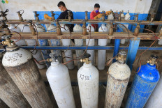 Workers refill empty medical oxygen cylinders in Banda Aceh city, Aceh on June 29. Banda Aceh is among the 43 cities and regencies in 20 provinces outside Java and Bali to impose tighter micro-scale public activity restrictions (PPKM Mikro) until July 20, after they were reclassified as “level 4” risk areas.