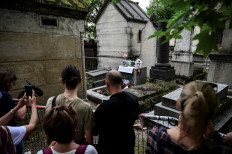 People gather by the grave of The Doors frontman Jim Morrison to commemorate the 50th anniversary of his death at the Pere Lachaise cemetery in Paris on July 3, 2021.