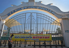 A resident walks in front of the closed gate of the Great Mosque of Banten in Kasemen, Serang, Banten on July 4, 2021. The government has extended the multi-tiered public activity restrictions until Aug. 9.