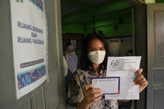 A student shows her COVID-19 vaccination card at state high school SMA 20 Jakarta on July 1, 2021. The Health Ministry has allowed students between the age of 12 to 17 to participate in the COVID-19 vaccination drive starting July 1.