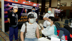 Prihadi (right, foreground), the head of the medical team of Alumni Kanisius Menteng 64 (AM64), the alumni association of Jakarta's Canisius College, administers a COVID-19 vaccine dose during the association's free public vaccination program. Looking on are AM64 chairman Irlan Suud (center, rear) and AM64 advisory board chairman Dani Wanandi (right, rear).