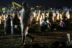 A gravedigger wearing personal protective equipment walks in the Muslim burial area provided by the government for COVID-19 victims, in Jakarta on July 7, 2021.