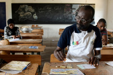 Senegalese scrabble players Issakha Marie Diallo (L), Abdoulaye Sylla (C) and Mouhamed Sy (R) sit in front of their boards while playing Scrabble in a classroom at School 23 in Guédiawaye, a suburb of Dakar, on July 3, 2021, where a post COVID-19 mini-tournament is organised.