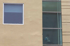 All Alone: An asymptomatic COVID-19 patient sits by the window of Hotel U Stay in West Jakarta on Wednesday. The hotel has been turned into an isolation facility for asymptomatic and mildly symptomatic COVID-19 patients from West and South Jakarta. 