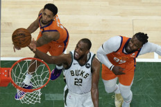 Khris Middleton #22 drives to the basket against Cameron Payne #15 and Jae Crowder #99 of the Phoenix Suns in Game Four of the NBA Finals at Fiserv Forum on July 14, 2021 in Milwaukee, Wisconsin. 