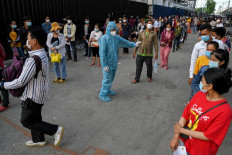 An official in personal protective equipment (PPE) manages the crowd as people queue to receive China's Sinopharm Covid-19 coronavirus vaccine in Phnom Penh on May 31, 2021, as part of the government's campaign to halt the rising number of cases of the virus.

