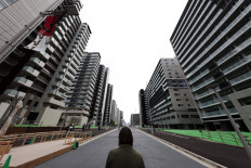  In this file photo taken on June 20, 2021, a reporter looks at the buildings which will host the athletes during the 2020 Tokyo Olympic Games, during a media tour of the Olympic Village in Tokyo. For athletes competing at the Tokyo Games, the Olympic Village will be almost all they see, with strict coronavirus rules preventing them from leaving the compound except to train and compete.