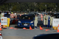 Health workers take samples from people in their vehicles at the Victoria Park Covid-19 testing station in Adelaide July 20, 2021, the latest Australian city to lock down after local coronavirus cases were detected. 