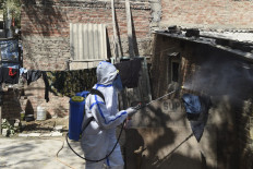 A health worker sprays sanitizer outside a house as a precautionary measure against the bird flu in Sola area, on the outskirts of Ahmedabad on March 5, 2021.