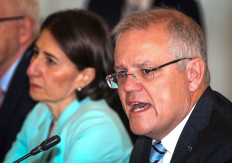 The Premier of New South Wales Gladys Berejiklian (left) reacts as Australian Prime Minister Scott Morrison speaks during the Meeting of the Council of Australian Governments (COAG) at Parramatta Stadium in western Sydney on March 13, 2020. 