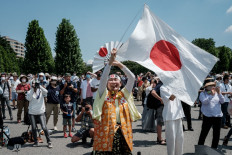 Olympic super-fan Kyoko Ishikawa (C), who has attended every Summer Olympics in the past 30 years, express her gratitude as Blue Impulse, Japan's Air Self Defense Force (JASDF) aerobatic team, performs a display to form the Olympic rings in the skies over Tokyo on July 23, 2021, ahead of the opening ceremony of the 2020 Tokyo Olympic Games.
