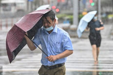 People cross the street in the wind and rain along in Ningbo on July 25, 2021, as Typhoon In-Fa lashes the eastern coast of China. 