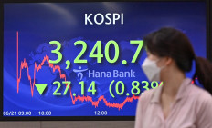 A currency dealer walks past a screen showing South Korea's benchmark stock index in a trading room at KEB Hana Bank in Seoul on June 21, 2021.